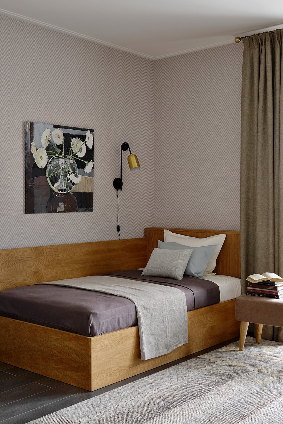 Зона вокруг кровати оформлена твидовыми обоями, что вместе с деревянной кроватью и льняными занавесками придает этой комнате уют.
