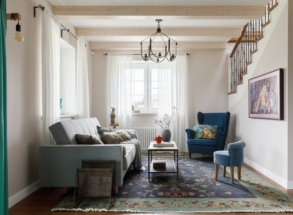 Участок стены между гостиной и лестницей оставили открытым, что добавило объема общему пространству. Красивые кованые балясины ограждения лестницы очень гармонично вписались в интерьер гостиной.