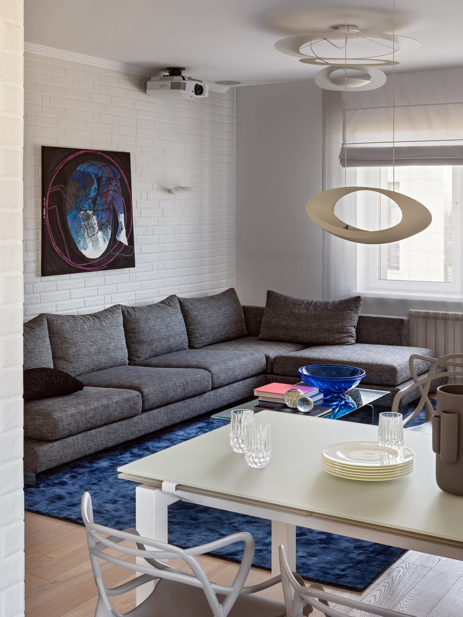 Стены в квартире все белого цвета, так хотел заказчик: даже декоративную плитку под кирпич взяли белую. Акценты сделали на светильниках и группах света. Только в спальне поклеили обои, чтобы выделить зону изголовья цветом.