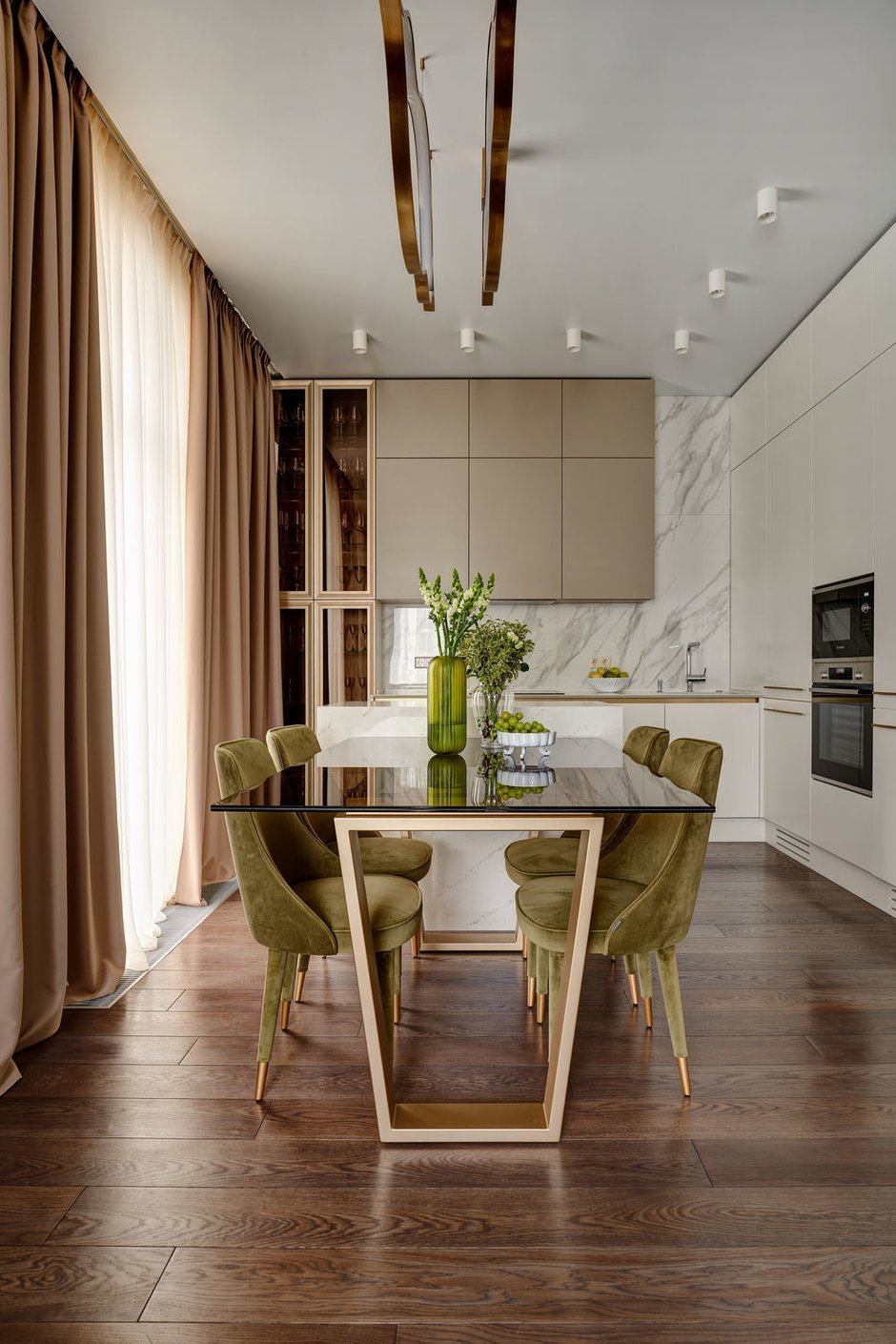 Зонирование кухни-гостиной выполнили с помощью кухонного острова. Им отгородили видимую часть кухни и добавили место хранения. К острову приставили обеденный стол, который легко можно передвигать.