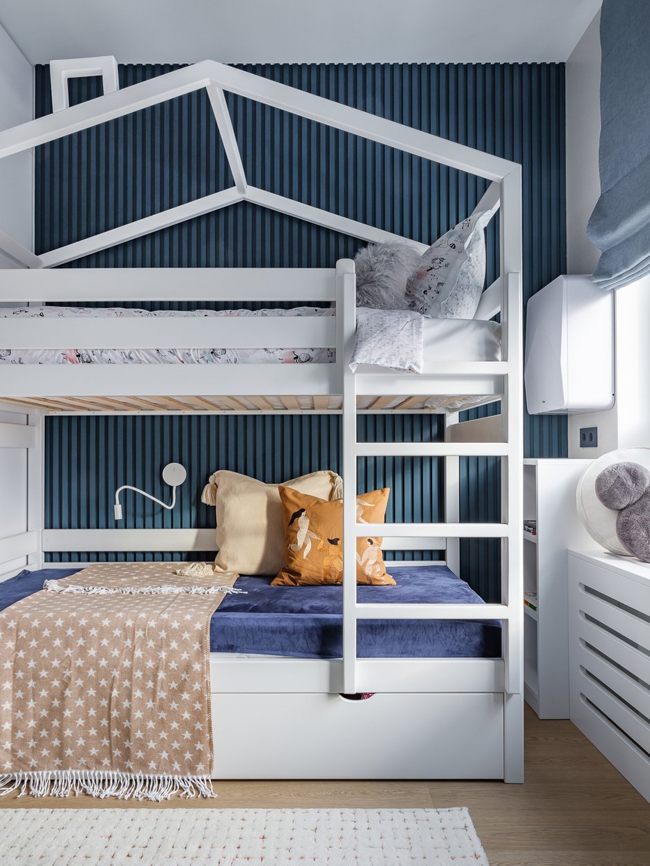 Акцентная стена за кроватью в детской — гипсовые панели, покрашенные синей краской. Еще одно интересное решение в детской: напротив рабочего стола использовали белые стеновые панели LEGO. Это идея заказчицы, интересный декоративный и функциональный прием.