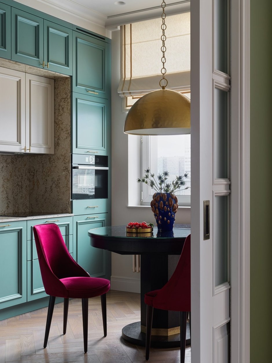 Цвет стен гостиной плавно переходит к бирюзово-голубым кухонным фасадам, эти оттенки гармонируют друг с другом.