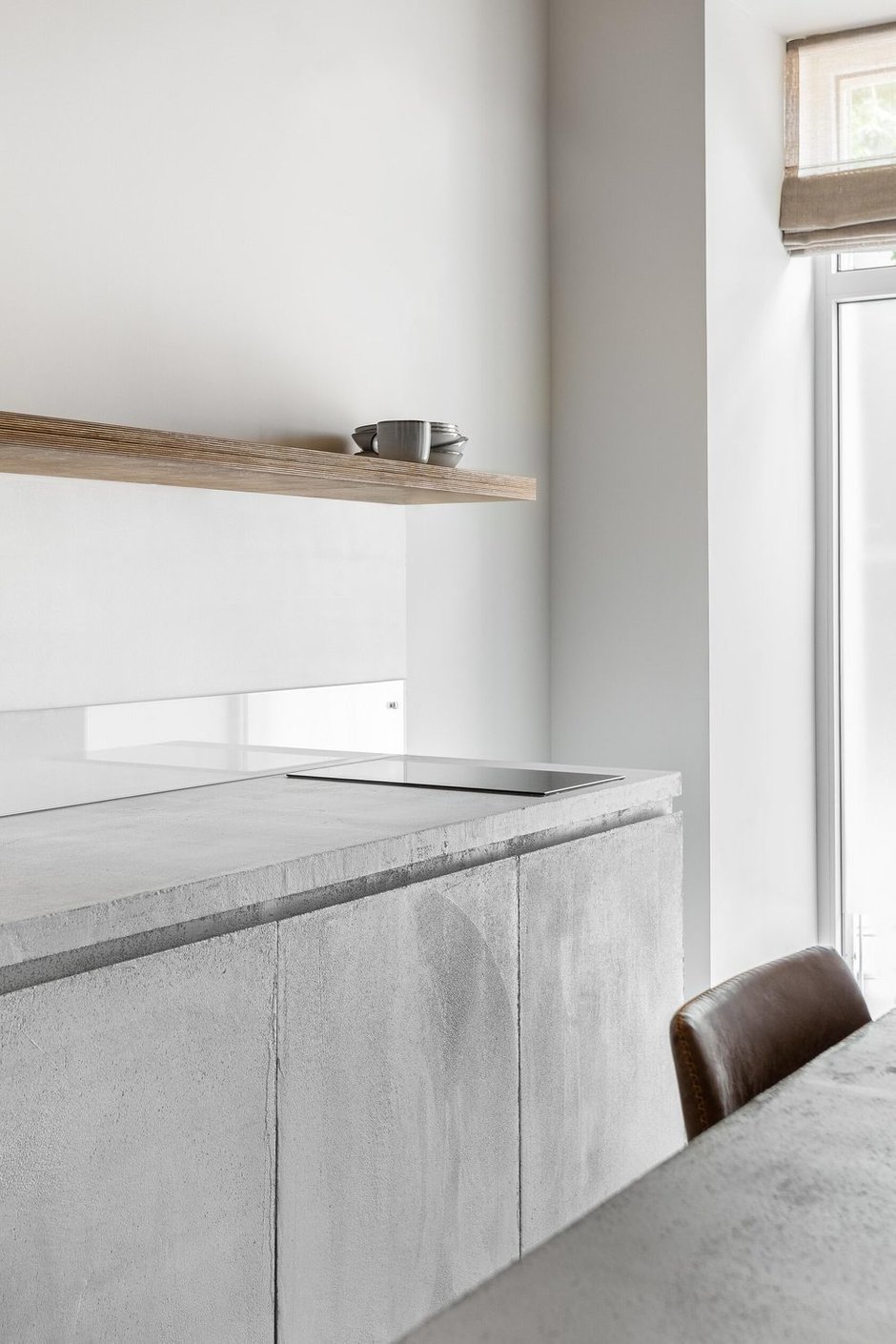 Кухонный гарнитур выполнен из фанеры, покрытой микробетоном. Это довольно бюджетное решение. В качестве фартука использовали невысокий бордюр из стекла.