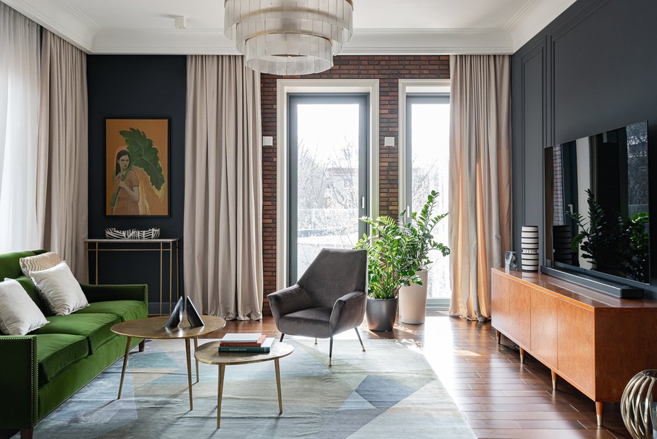 В гостиной зоне отлично сочетаются штукатурка графитового цвета и имитация кирпичной кладки. Для контраста выбрали светлые гардины.