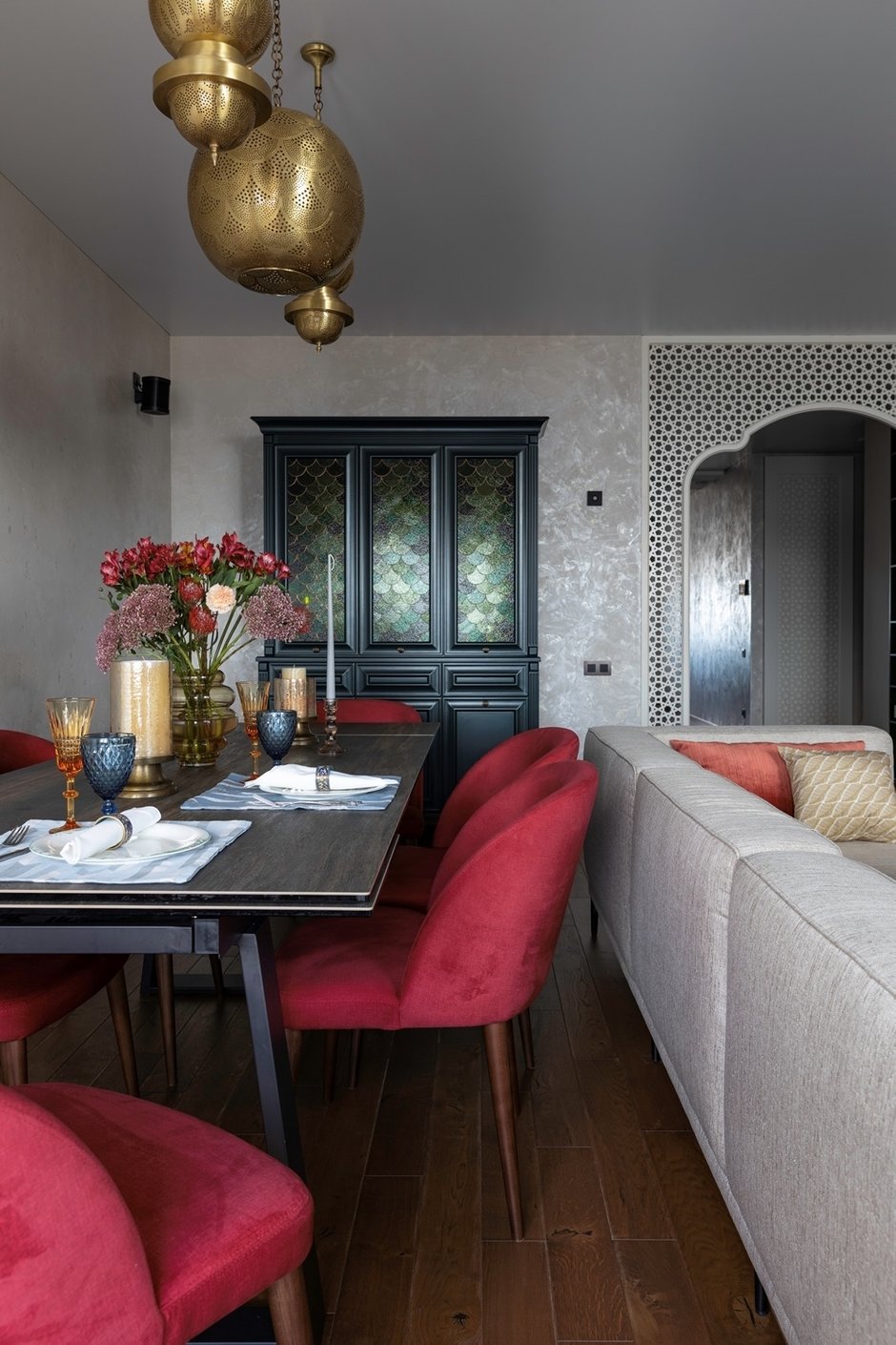 Сервант был сделан на заказ по примерам антикварных вариантов. Витражное стекло в распашных дверях заказчица привезла из Москвы из той мастерской, которая смогла выполнить такой рисунок. Люстры — это ручная работа мастеров из Марокко.