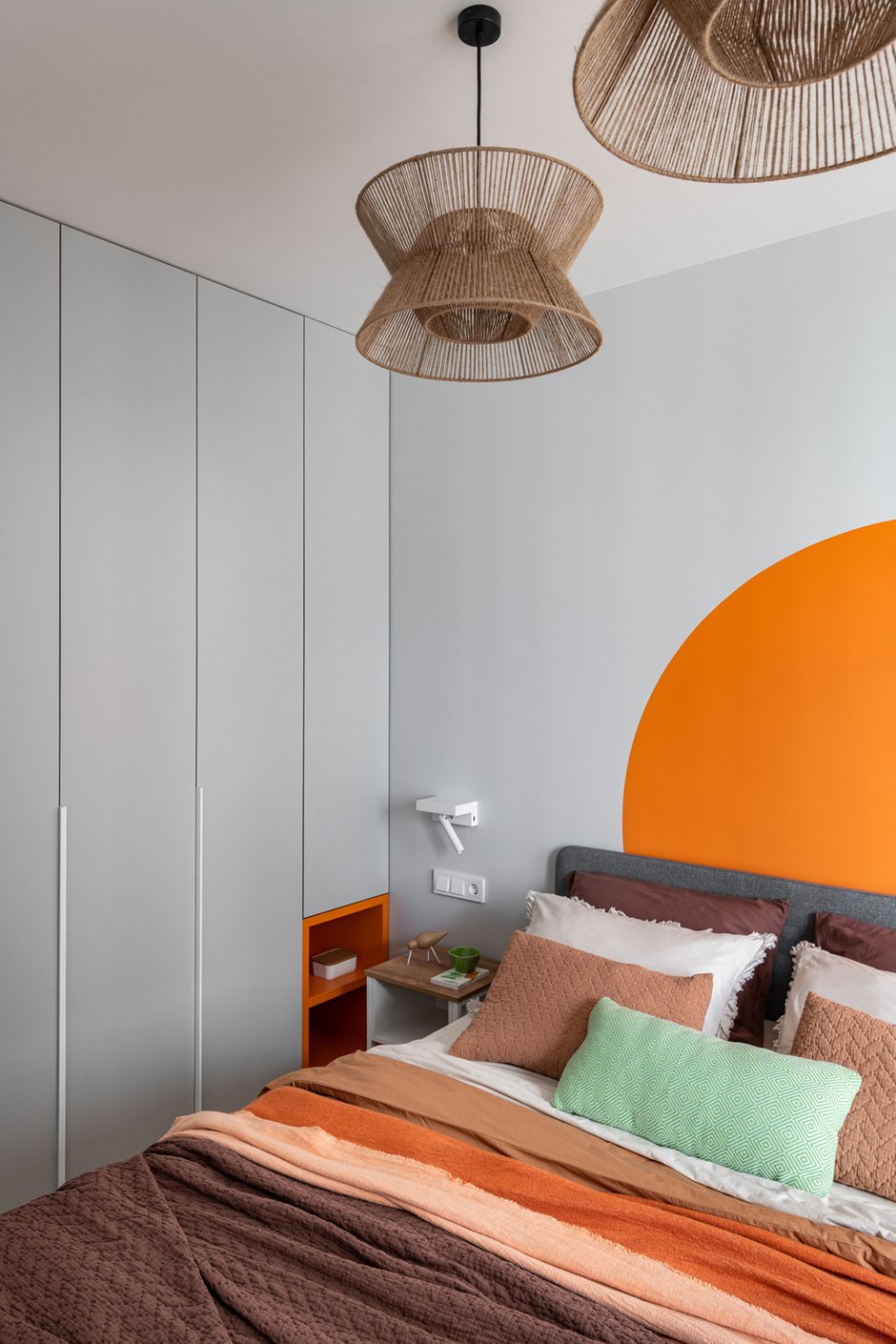 В прихожей и коридоре выделили сочным оранжевым цветом системы для хранения, а в одной из спален получилось яркое апельсиновое солнце за изголовьем кровати. 
