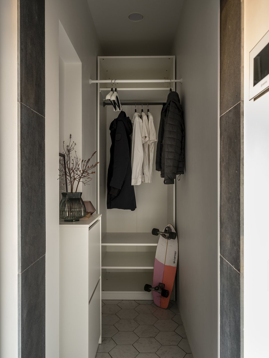 При входе есть отдельная гардеробная, где можно повесить верхнюю одежду. Гардеробная узкая, поэтому в дальней части располагается шкаф для несезонного хранения, а перед ним предусмотрен ряд вешалок для повседневной верхней одежды.