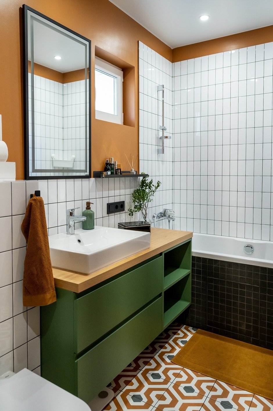 Настенное покрытие в зоне туалета, ванной и душевой — керамическая плитка. Напольное покрытие — керамогранит. Пол в душевой выложен черной мозаикой, она же украшает фасад ванной. Остальное стеновое покрытие — это влагостойкая краска.