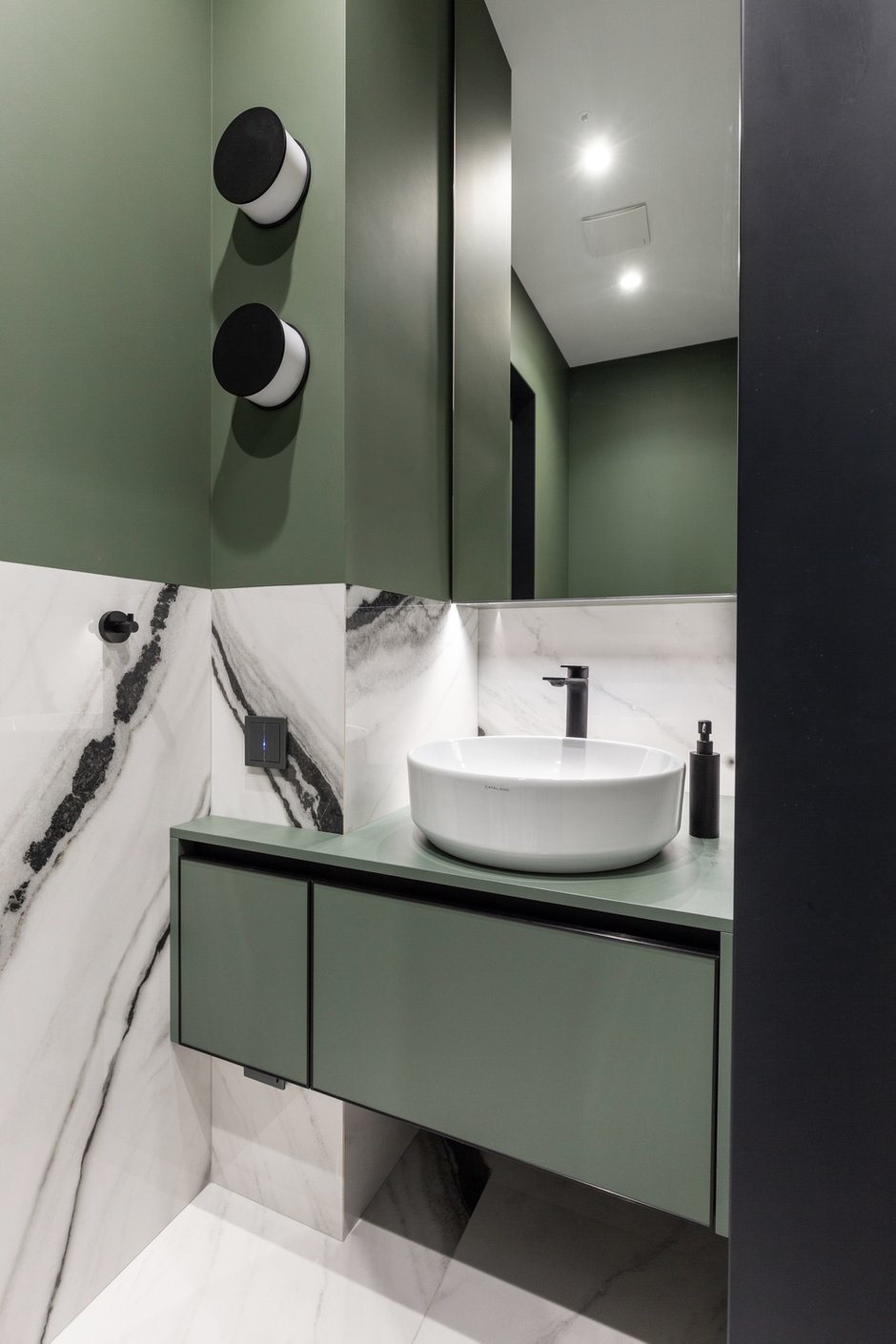 Гостевой санузел оформили с использованием фактуры мрамора, сложного серо-зеленого цвета и черных элементов.