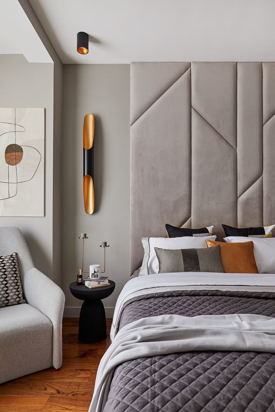 В спальне изголовье кровати выполнили из мягких панелей. Черные и золотые элементы добавили динамики и контраста, сделав пространство более фактурным.