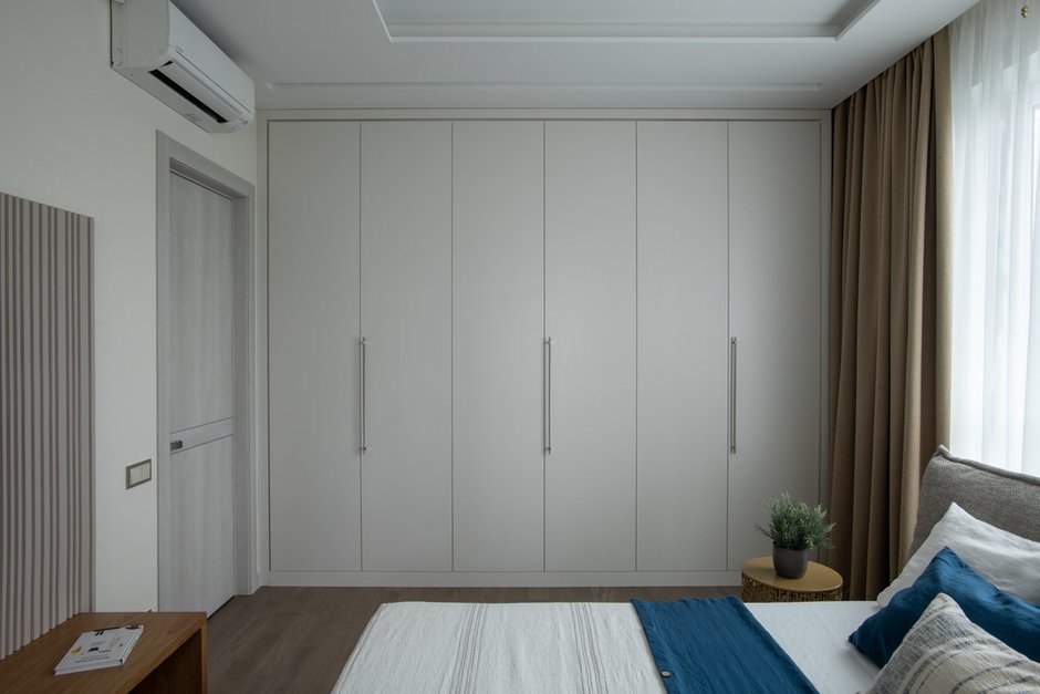 В спальне шкаф сделан без антресоли и выкрашен в цвет стен, чтобы максимально скрыть его.