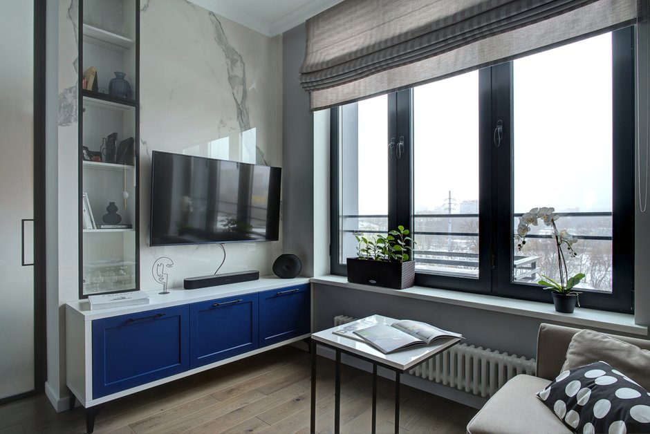 «При использовании крупноформатного керамогранита важно учесть высоту помещения. У выбранного нами керамогранита высота одного листа была 2,78 м — это идеально подошло под наш проект (за вычетом плинтуса и карниза высота стены под отделку керамогранитом 2,75 м). Вся суть отделки стены за ТВ была в имитации натурального мрамора. Если бы пришлось добирать высоту кусками керамогранита, появились бы швы и вся идея развалилась», — делятся дизайнеры.