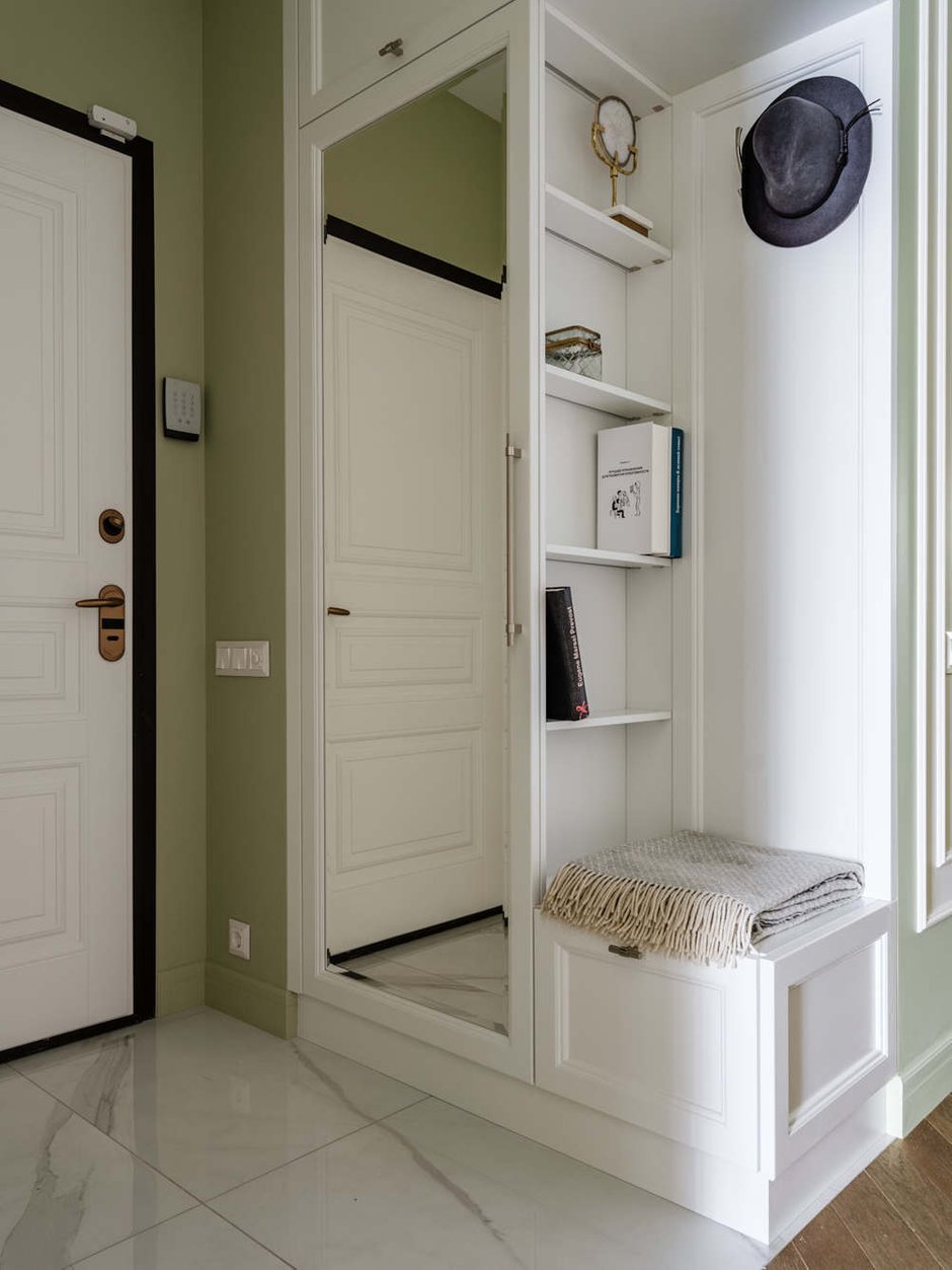 В прихожей разместился небольшой шкаф с сиденьем и открытыми крючками, напротив входной двери находится гардеробная.