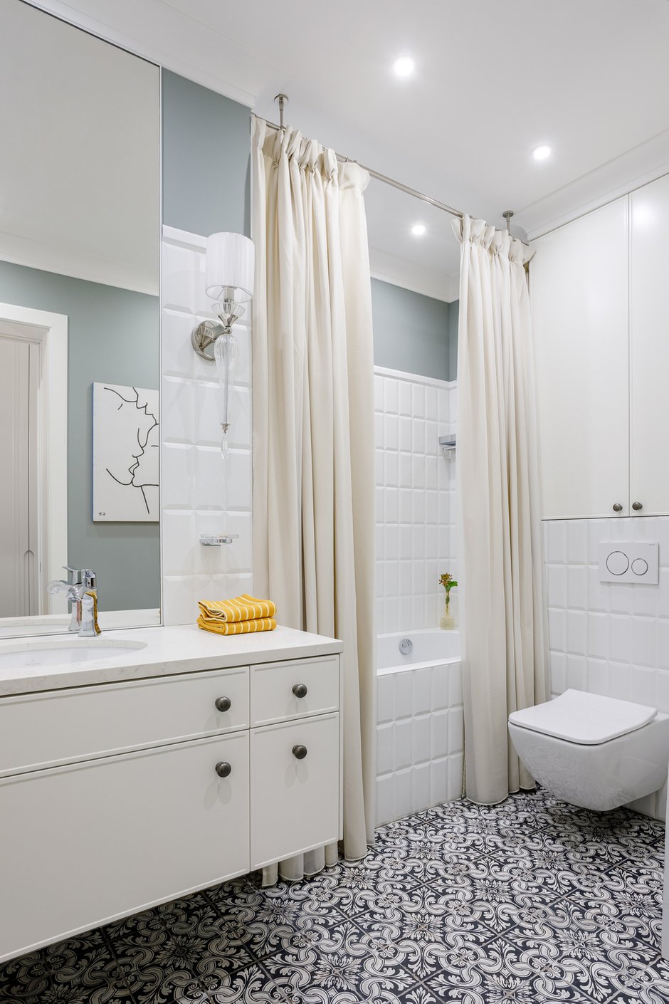 Над инсталляцией унитаза расположили шкафчик, в нем спрятали гребенки. Справа от унитаза — шкаф со стиральной и сушильной машинами, а над ними полки для хранения.