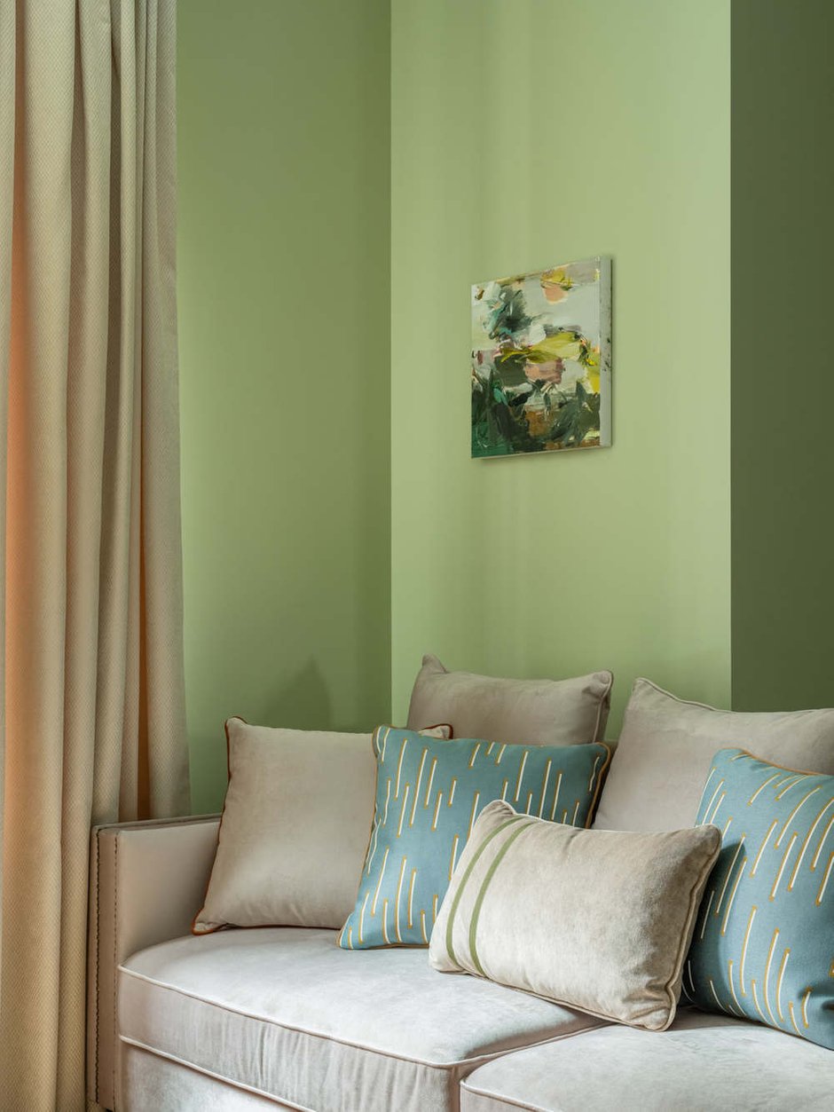 Для отделки стен гостиной выбрали английский зеленый в сочетании со светлыми вставками внутри молдингов. На полу паркетная доска натурального светлого оттенка дуба, который гармонично дополняет зеленый оттенок стен, а также оттеняет яркие терракотовые акценты.