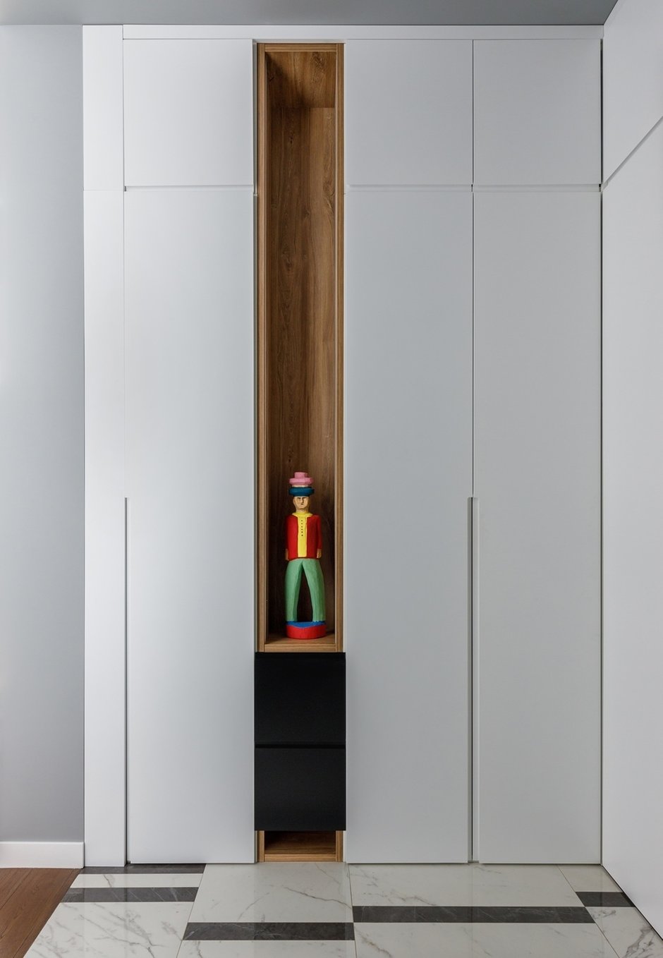 Чтобы шкаф смотрелся легче, сплошные фасады комбинировали с нишами цвета натурального дерева. 