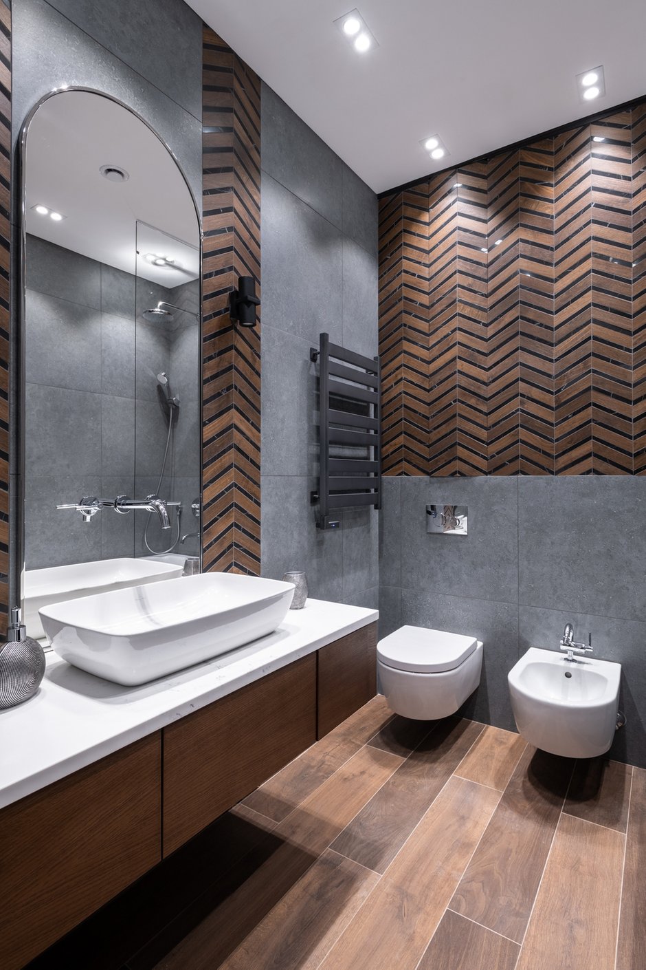 В сером санузле акцентом стала плитка-мозаика Atlas Concorde, которая соединила в себе дерево и мрамор. Смотрится очень эффектно и задает определенный ритм, а зеркало со смесителем на нем — это особая любовь.