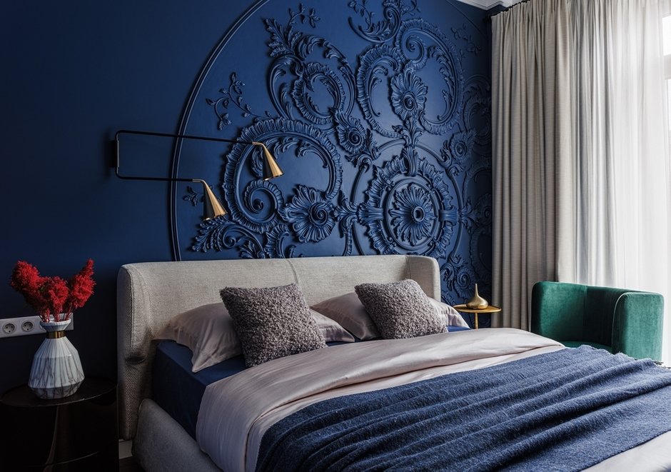 Классическая розетка за кроватью стала самым эффектным решением в интерьере.  Стена была выкрашена в насыщенный синий цвет, усиливающий впечатление.